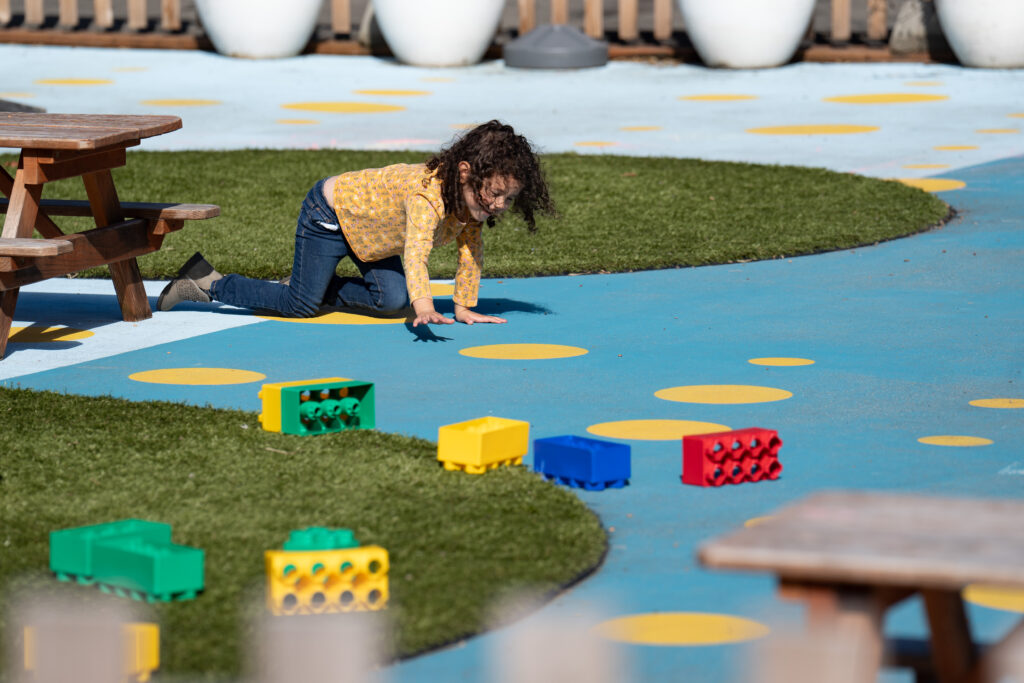 kid playing outside on a blue surface