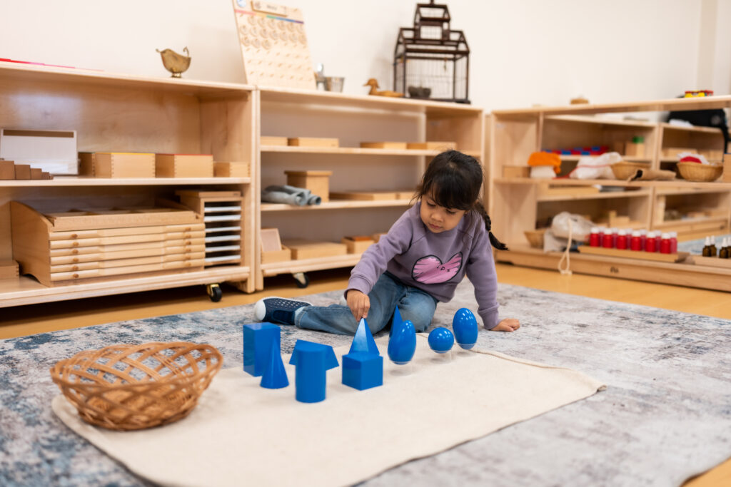 a kid playing with toy shapes in a classroom